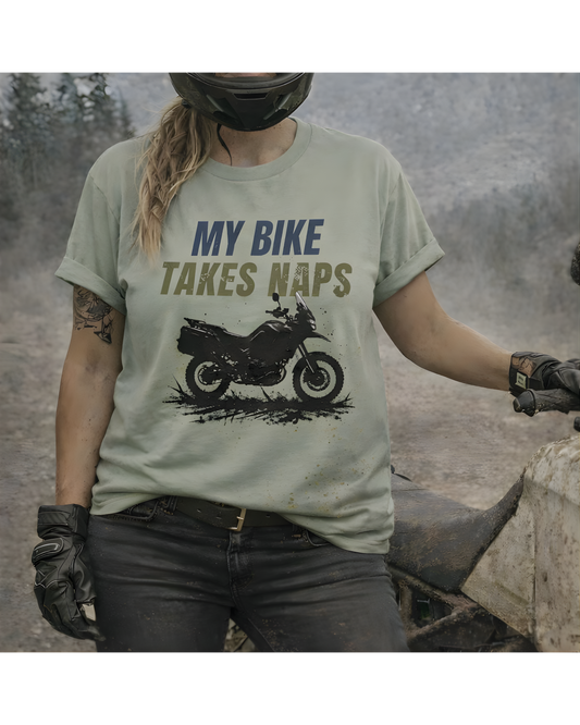 Women ADV rider wearing a t-shirt with 'My Bike Takes Naps' graphic and text, standing outdoors.